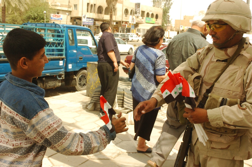 SFC Alex Mejia distributes Iraqi flags to people