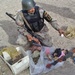 A soldier inspects a flare gun and AK-47 rifle found