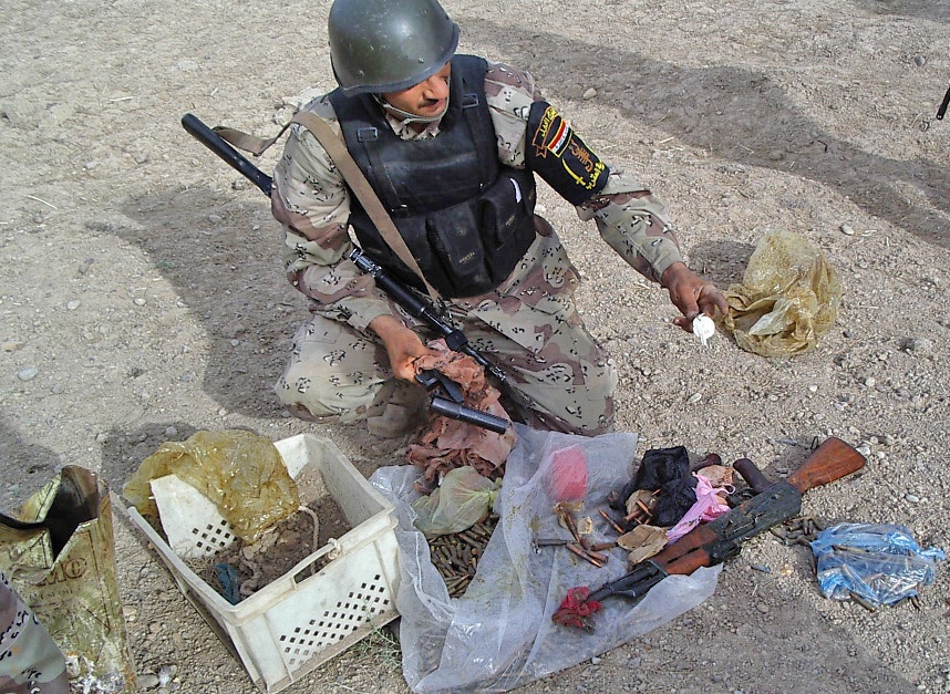 A soldier inspects a flare gun and AK-47 rifle found