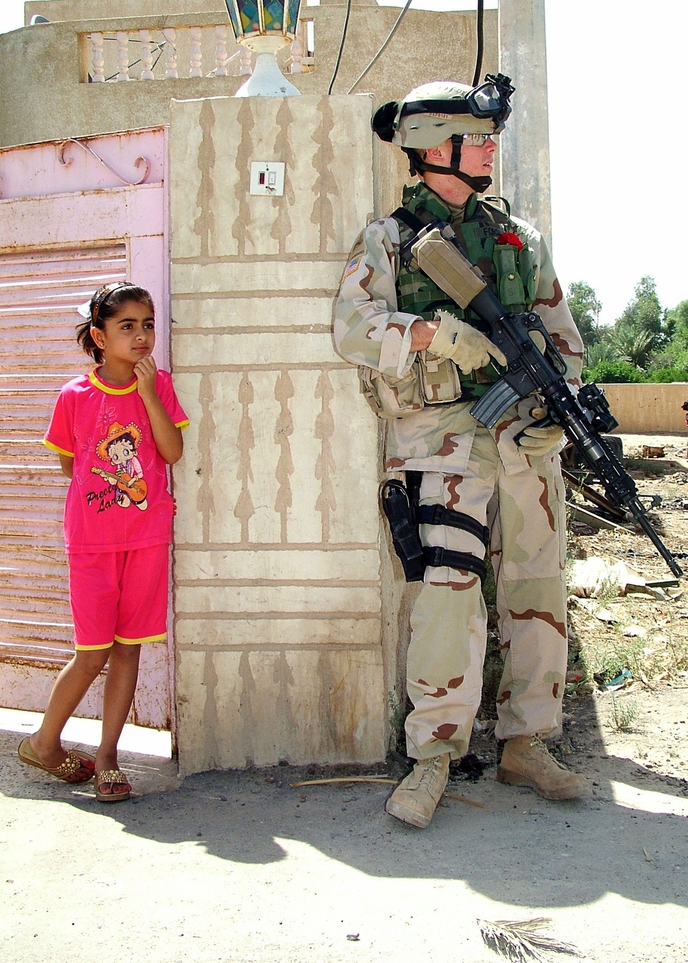 Sgt. Ford watches a neighborhood street with an Iraqi girl