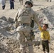 A soldier (high-fives) a local Iraqi boy