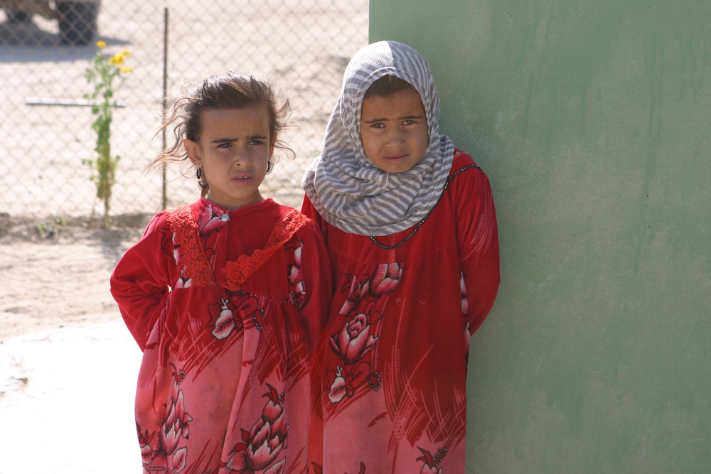 Two local village girls watch as service members visit