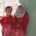 Two local village girls watch as service members visit