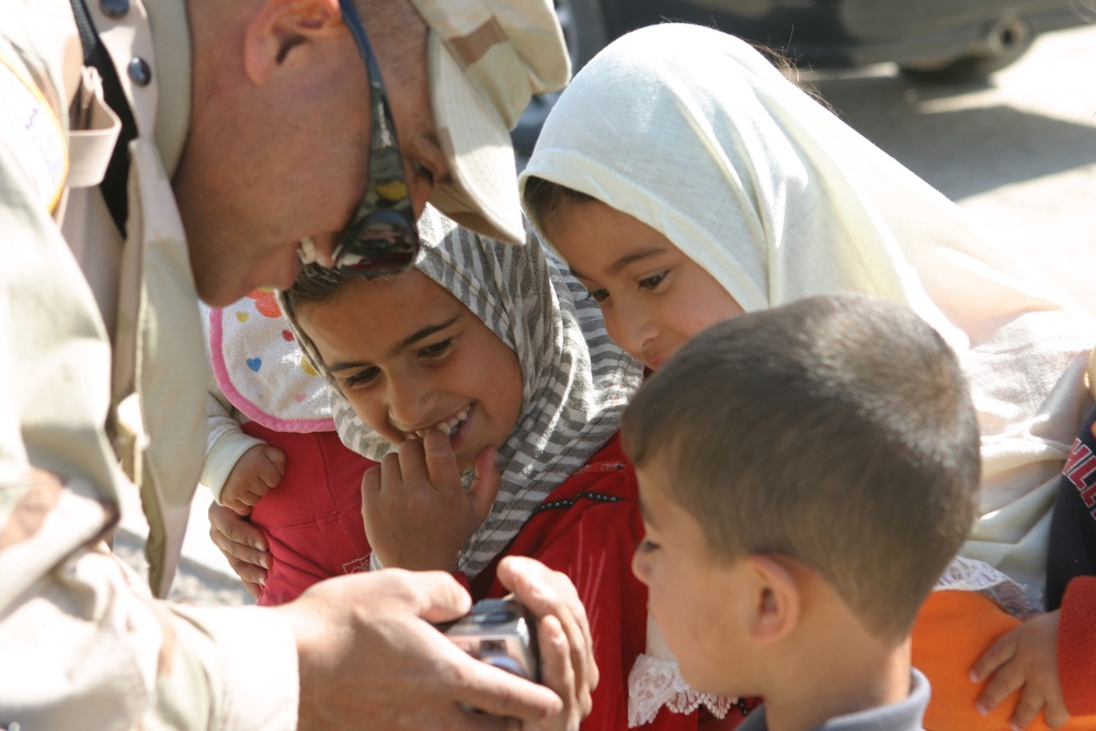 SFC Jesse Ortiz shows children their pictures he took