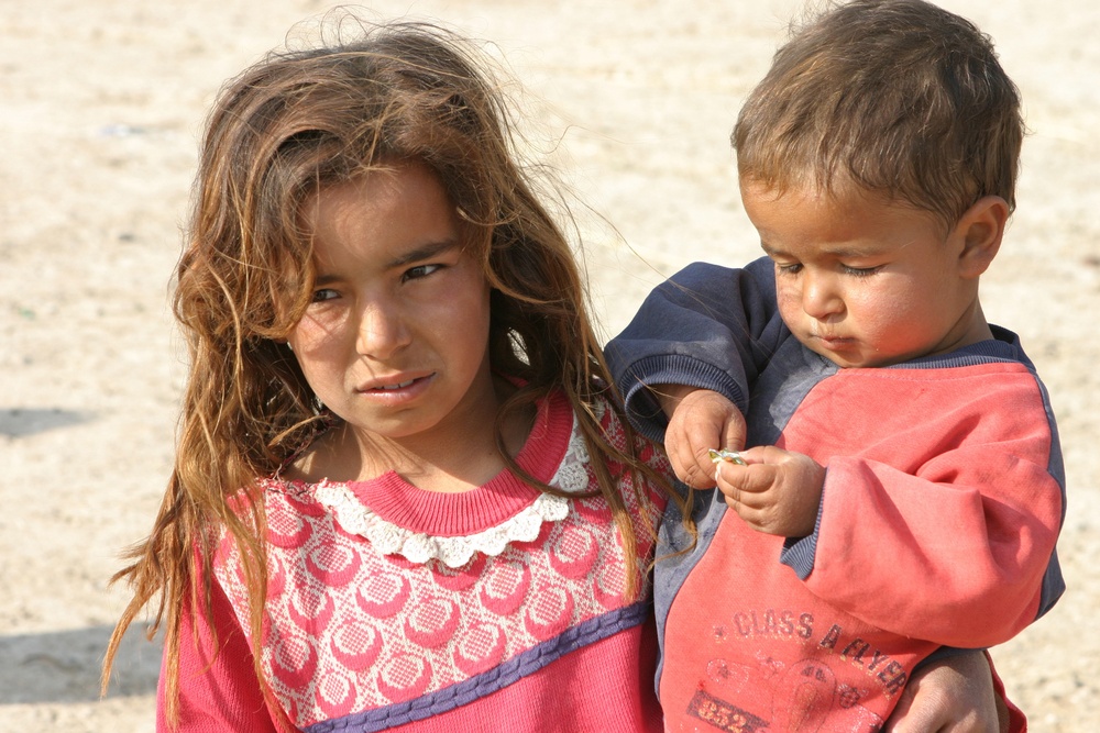 An Iraqi girl holds her brother to keep an eye on him