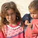 An Iraqi girl holds her brother to keep an eye on him