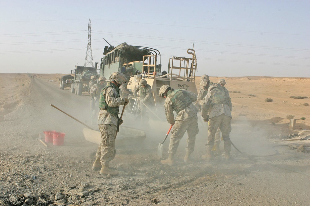 Marines use shovels and jackhammers to work on the roads