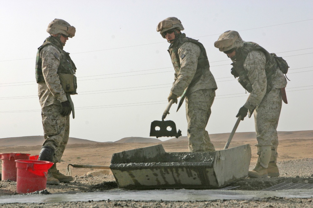 Marines mix concrete to pour into a crater in Western Iraq