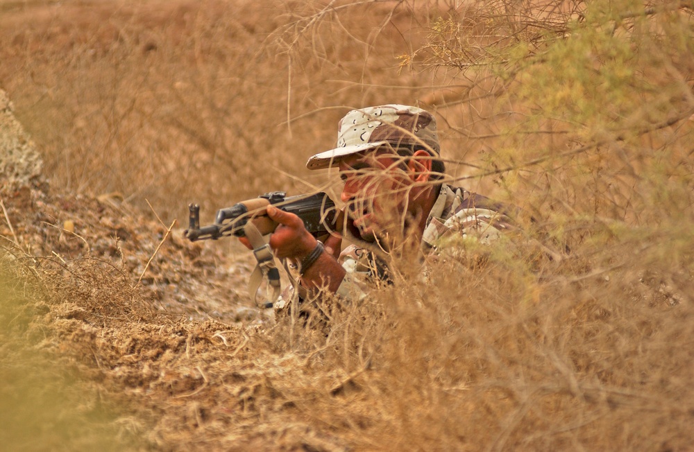 An Iraqi army soldier takes cover during a simulated