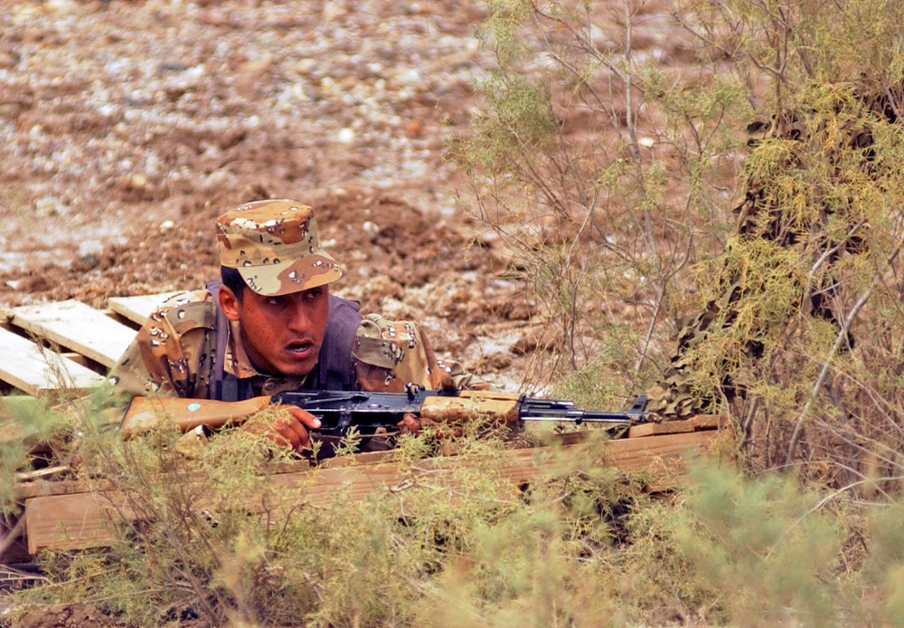 An Iraqi army soldier takes cover during a simulated fire fight