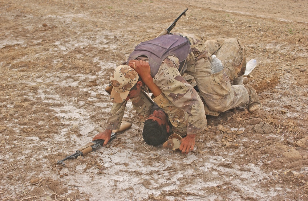 An Iraqi army soldier drangs a soldier to cover