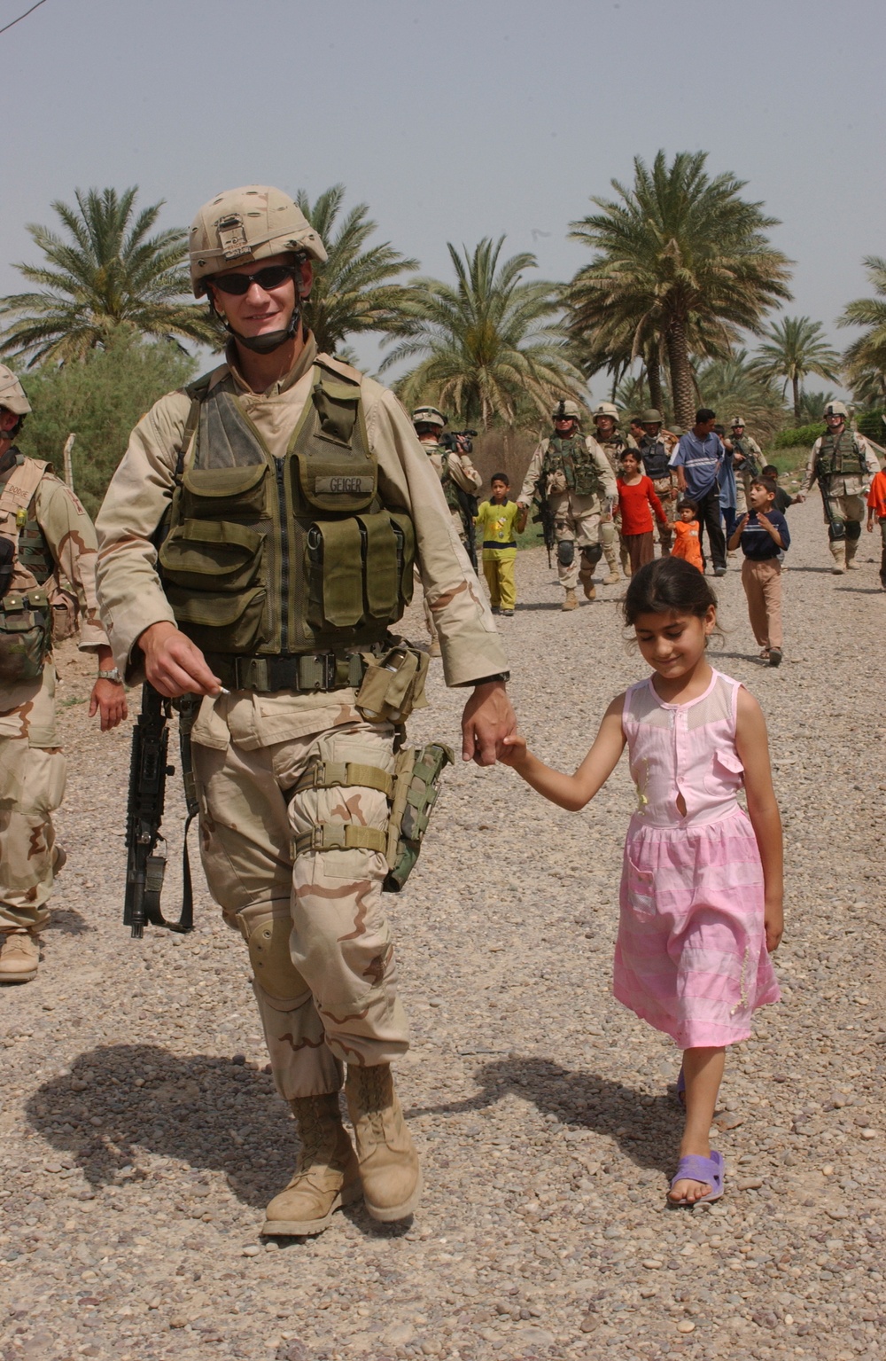 Cpl. Michael Geiger hold a little Iraqi girls hand