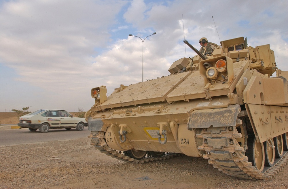 A gunner watches as an Iraqi civilian vehicle drives past