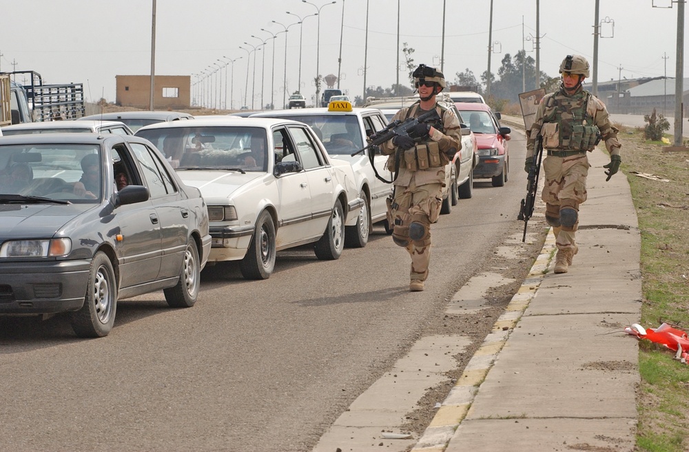 Soldiers visually inspect vehicles waiting to enter