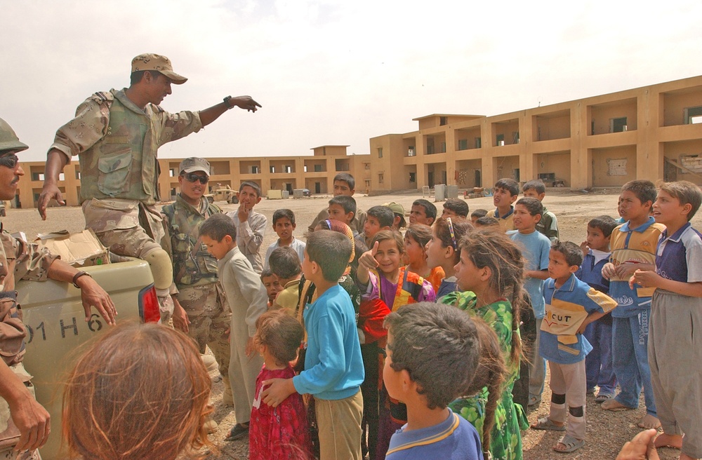 Iraqi children crowd around an Iraqi Army vehicle