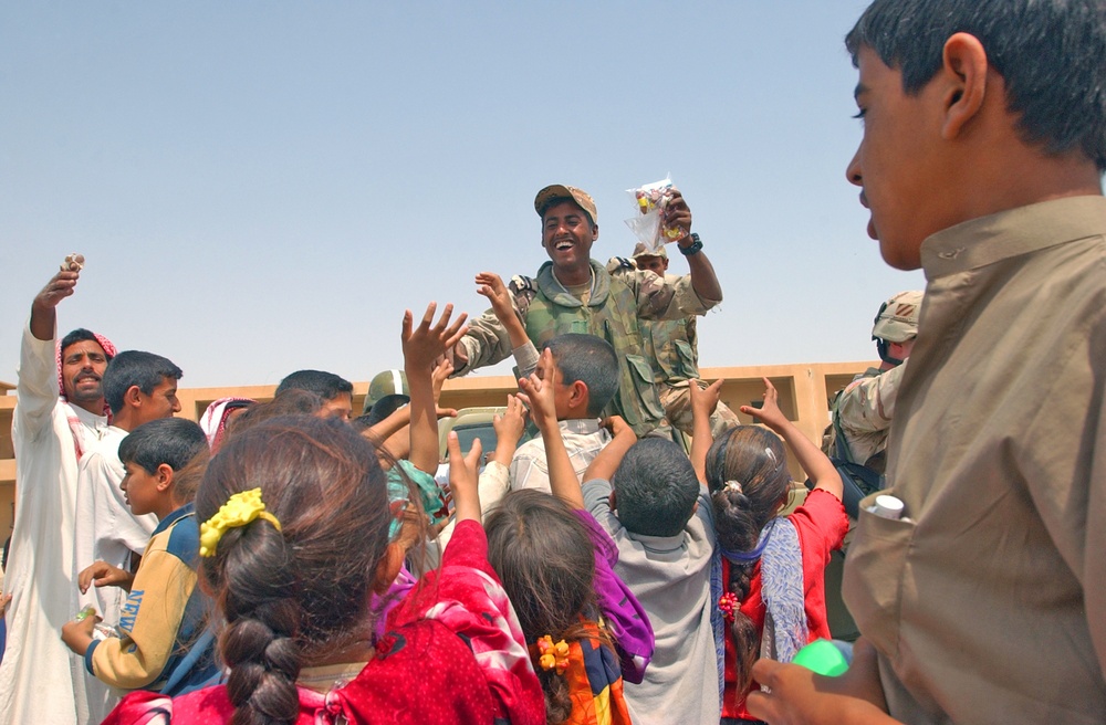 Iraqi children crowd around an Iraqi Army vehicle