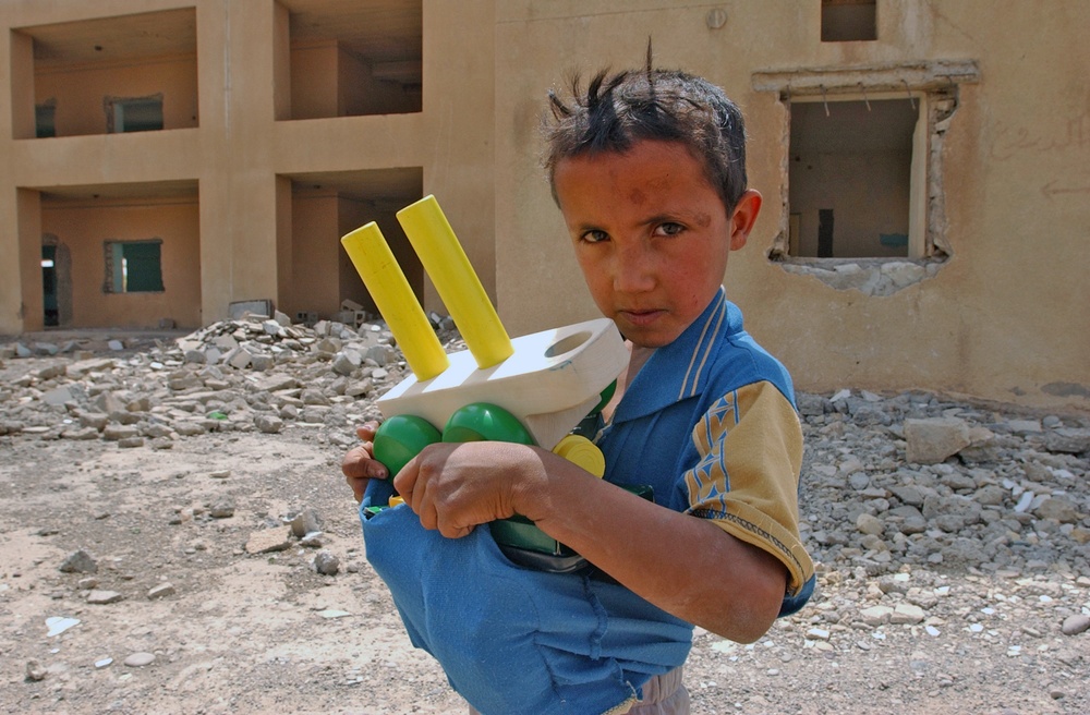 A small Iraqi boy holds toys and candy