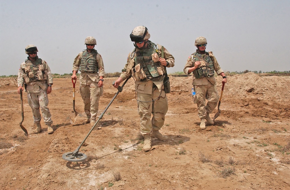 Pvt. Mark Hughes uses a mine detector to search