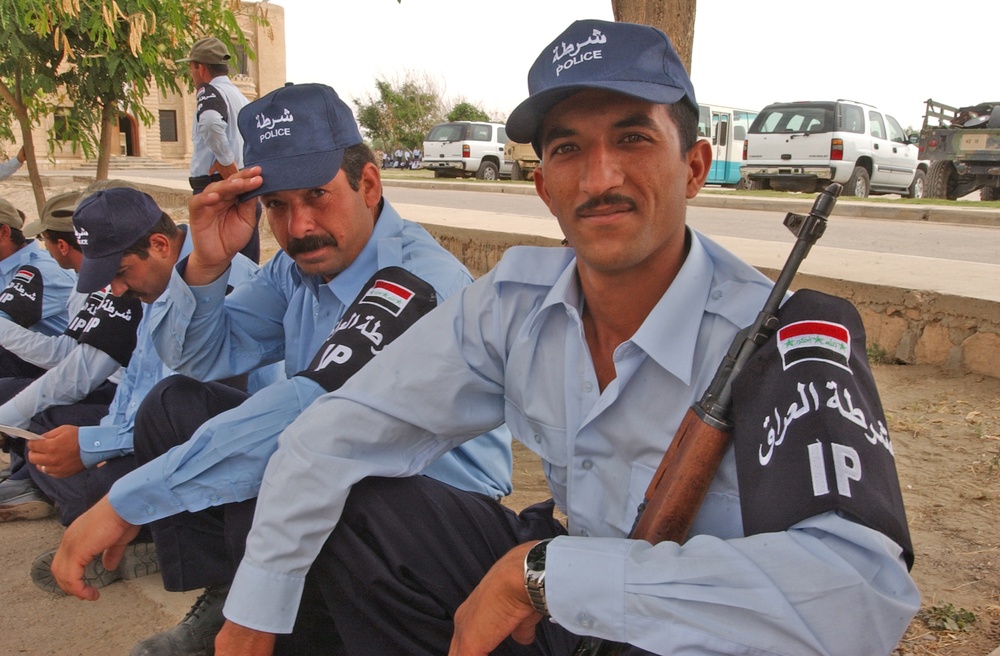 Iraqi Police recruits wait in the shade of a tree