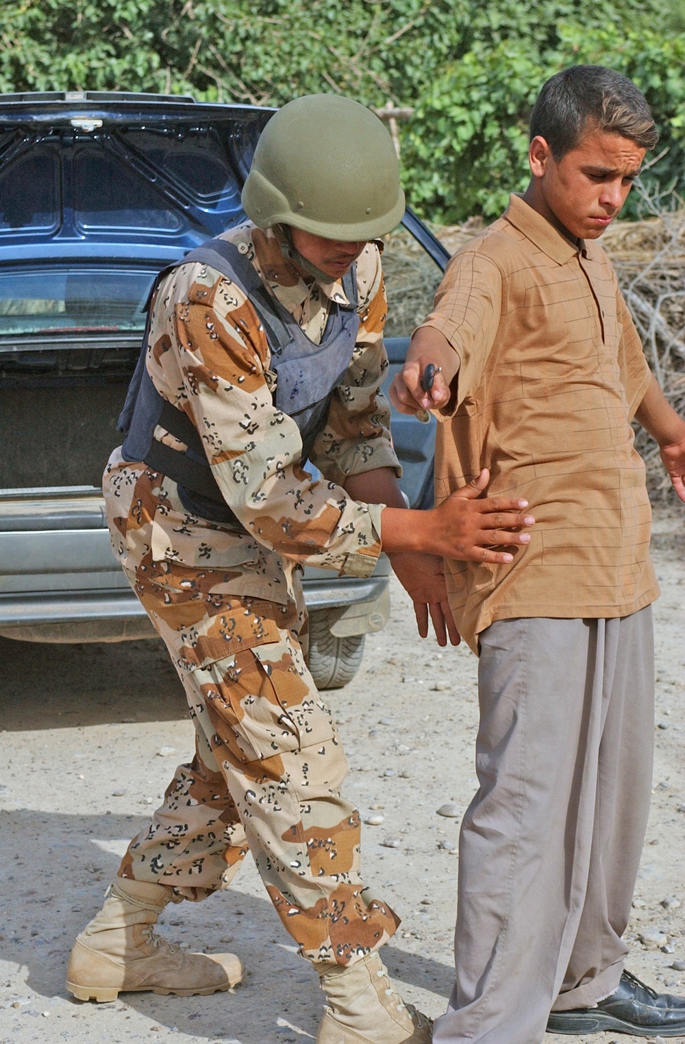 An Iraqi Army soldier pats-down an Iraqi civilian