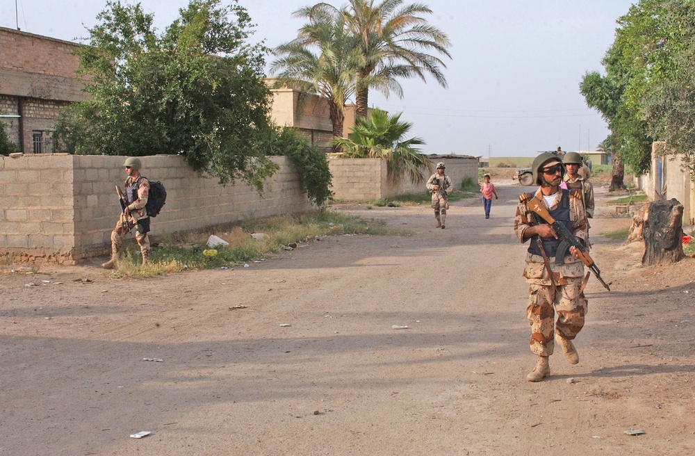 Soldiers conduct a foot patrol through a small town