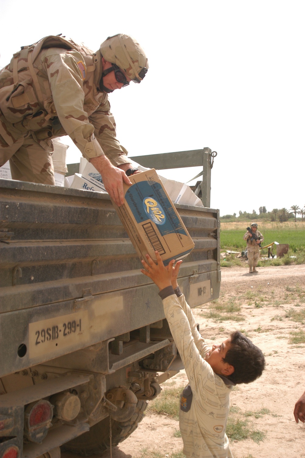 SFC Odoardi gently hands an eager boy a case of cookies