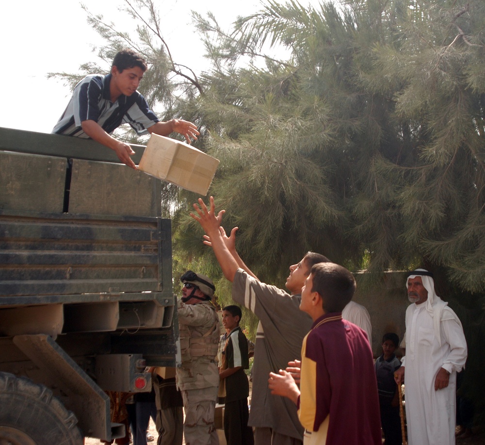 An Iraqi teenage boy tosses a case of cookies