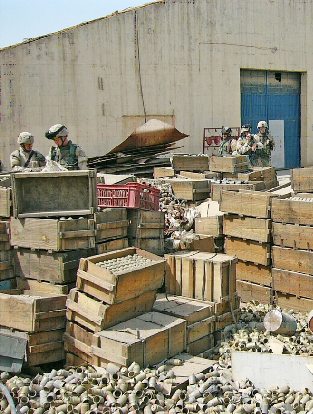 Soldiers inspect crates filled with sub-munitions and fuzes