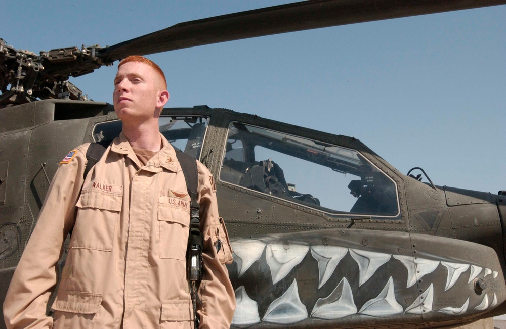 WO Joseph Walker stands next to an AH-64 Apache