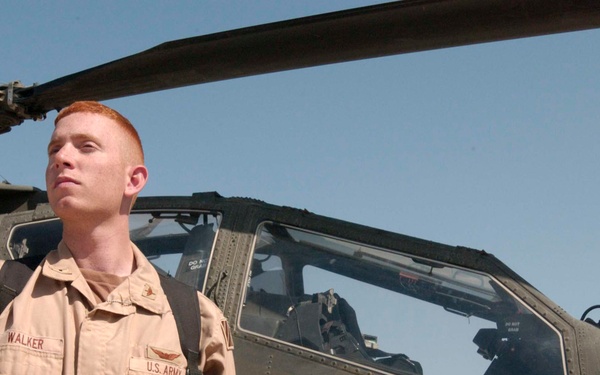 WO Joseph Walker stands next to an AH-64 Apache