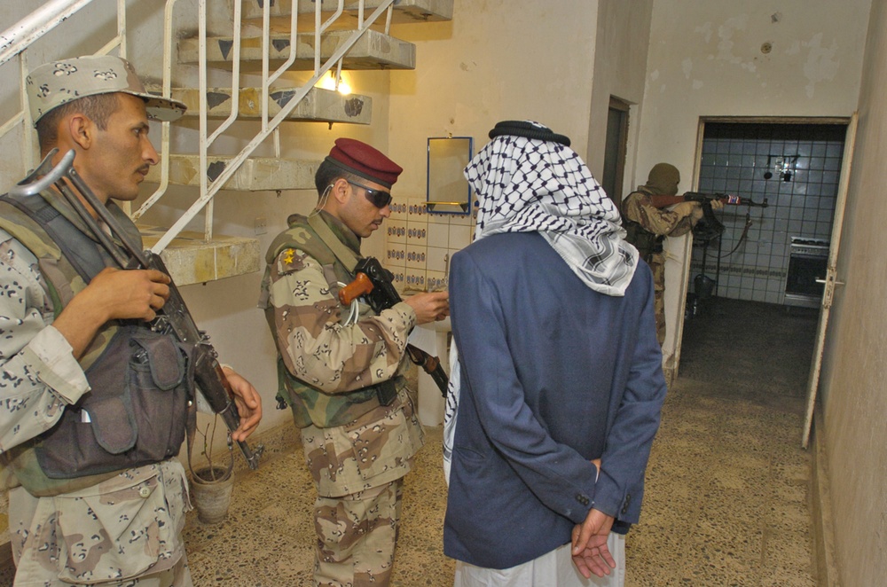 Iraqi army soldiers inspect houses and identification cards