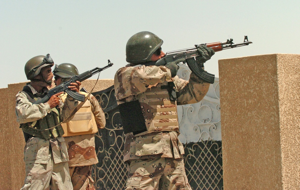 Iraqi Army cover their fellow soldiers as they search