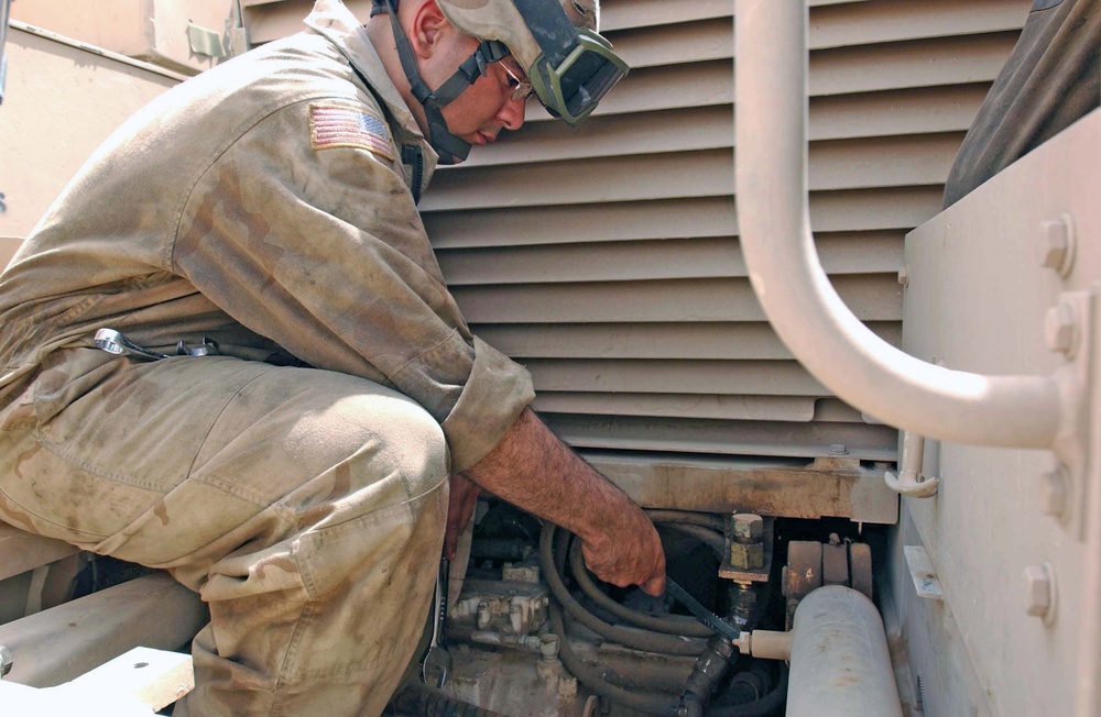 Spc. Aybar tightens a hose on the final drive assembly