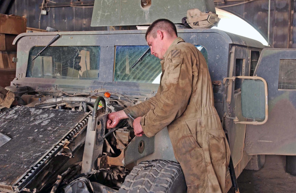 Spc. John Harris works on a Humvee in the maintenance area