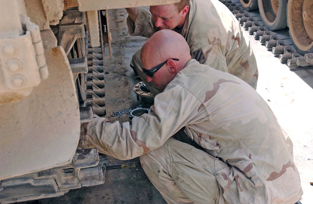 Soldiers insert a pin in the track on an M2 Bradley