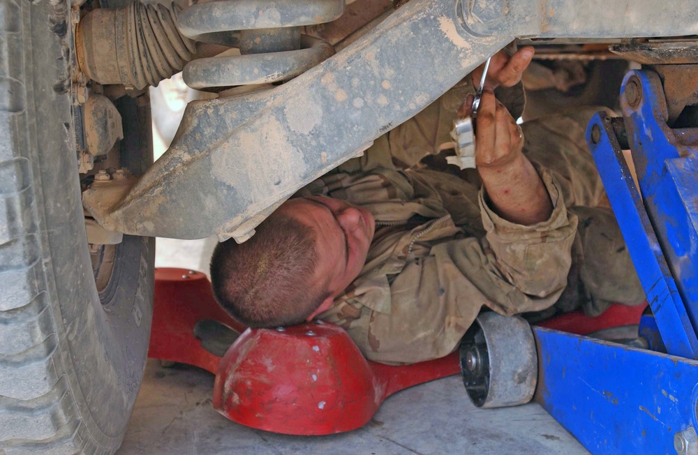 Pvt. Weston tightens a bolt underneath a Humvee