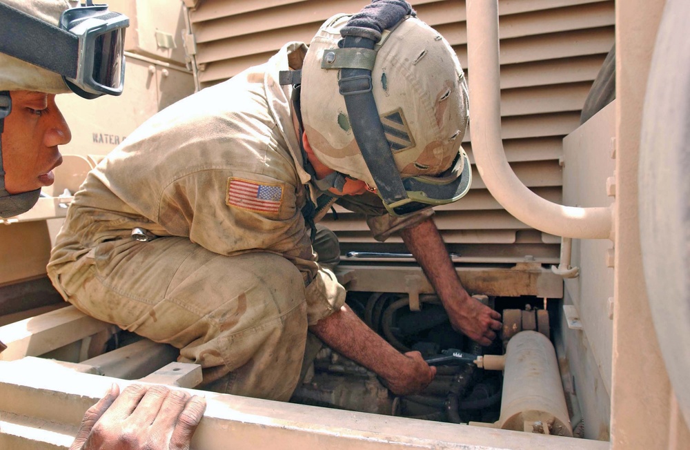 Spc. Aybar tightens a hose on the final drive assembly