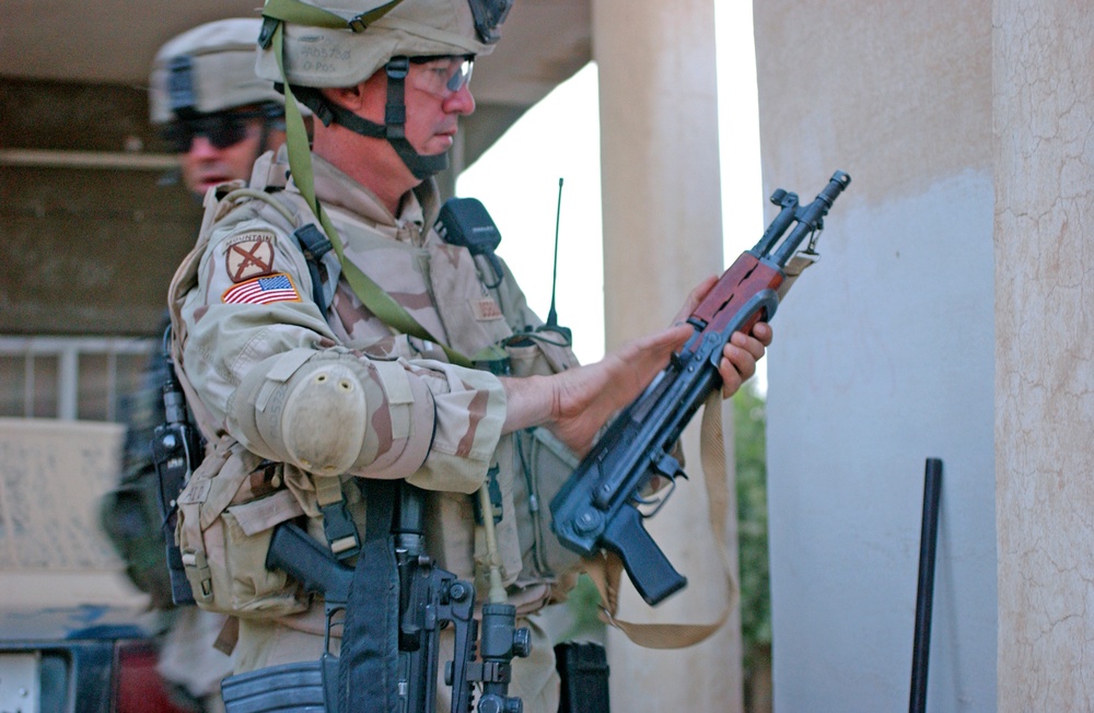 Sgt. 1st Class Phill Osbourn inspects an AK 47 found