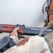 A soldier examines an AK 47 found during a raid
