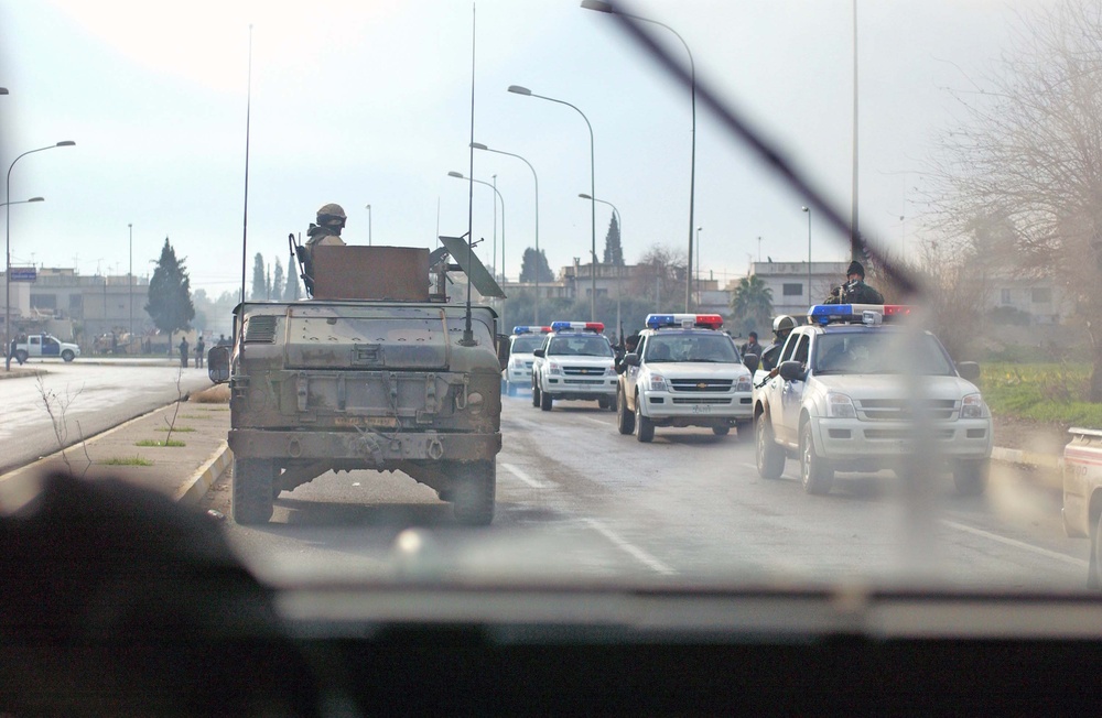 An American hummer convoy drives past an Iraqi Police