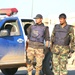 Two Iraqi Police Officers, stand outside their vehicle