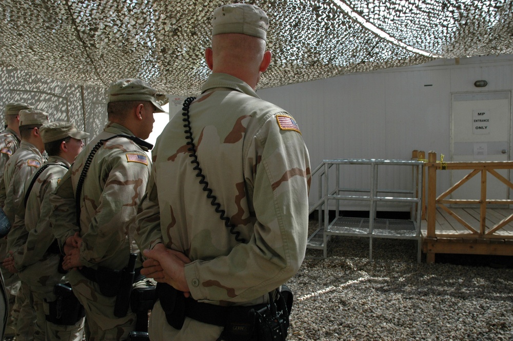 Military police officers stand in a formation outside