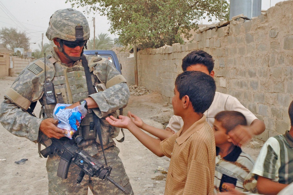 2nd Lt. Jason C. Royal hands out candy to Iraqi Children