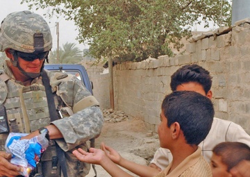 2nd Lt. Jason C. Royal hands out candy to Iraqi Children
