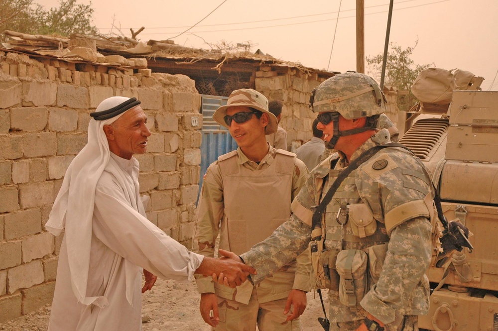 2nd Lt. Jason C. Royal shakes hand with an Iraqi
