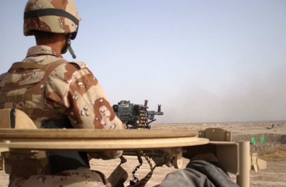 An Iraqi truck gunner mounted on top of a 2nd MTR truck unloads a belt of a