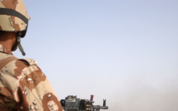 An Iraqi truck gunner mounted on top of a 2nd MTR truck unloads a belt of a