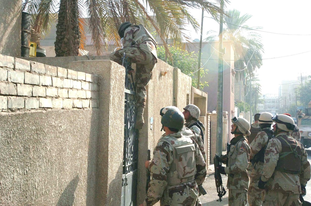 Troops hop a gate during a search