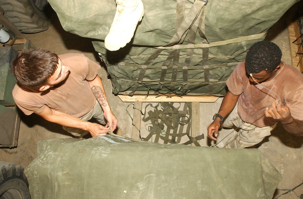 PFC Hutchinson and SPC Miller tie canvas cargo covers together to encase a