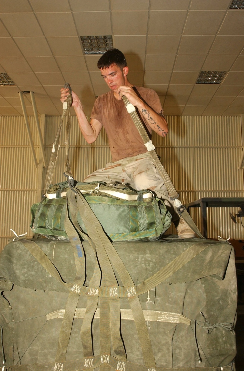 PFC Hutchinson gathers the tops of a cargo net to attach it to a parachute